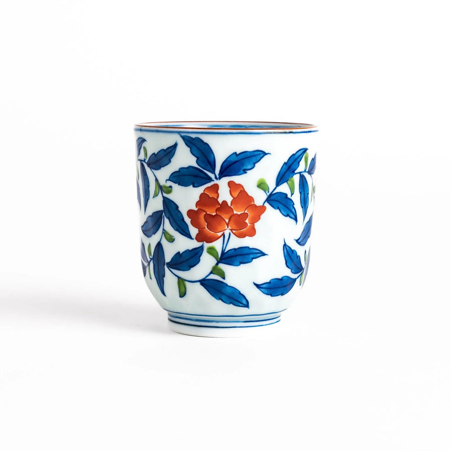 Porcelain teacup with vivid blue and orange floral design and green leaves showing fine Japanese artistry.