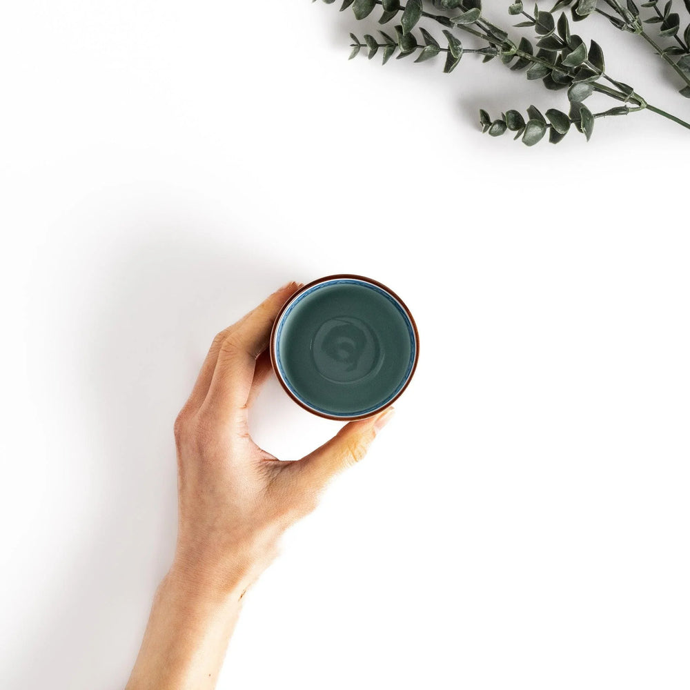 Porcelain teacup with vivid blue and orange floral design and green leaves showing fine Japanese artistry.