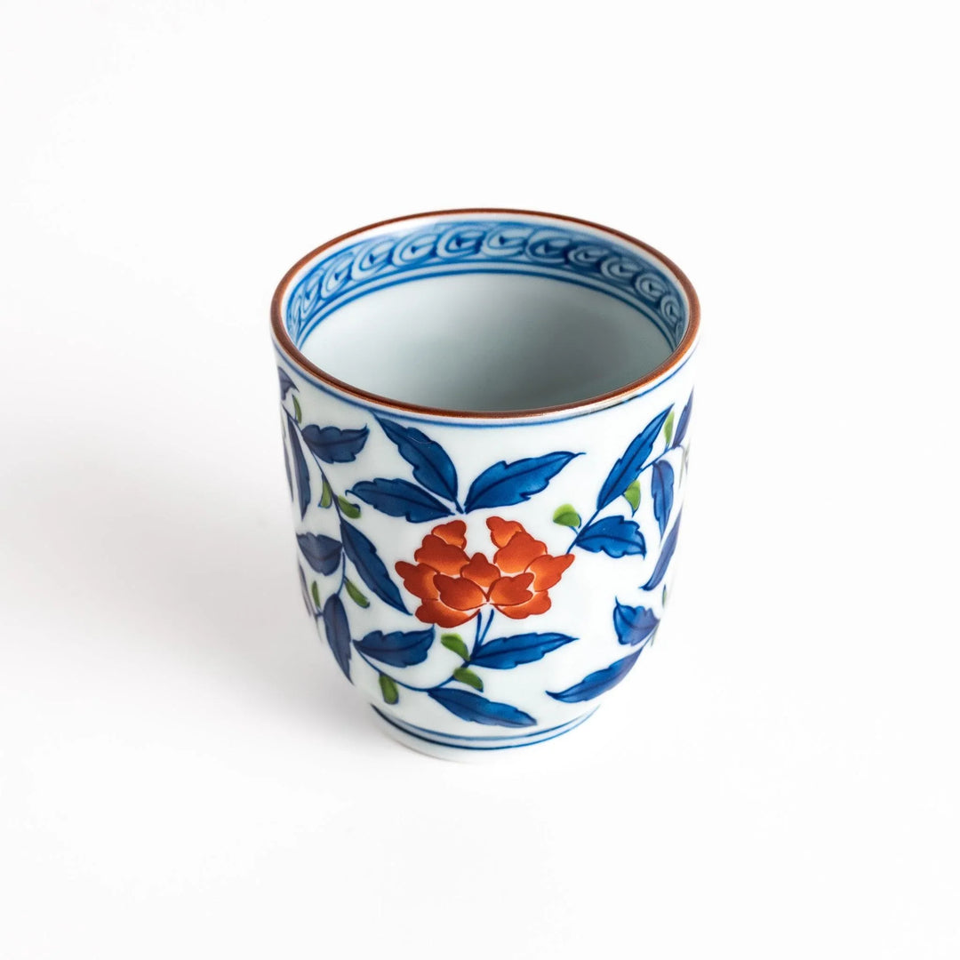 Porcelain teacup with vivid blue and orange floral design and green leaves showing fine Japanese artistry.