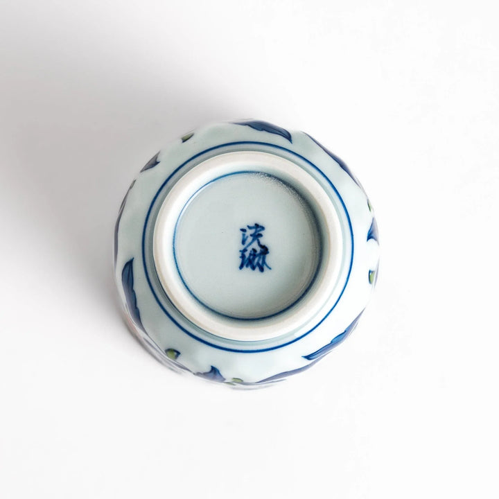 Porcelain teacup with vivid blue and orange floral design and green leaves showing fine Japanese artistry.