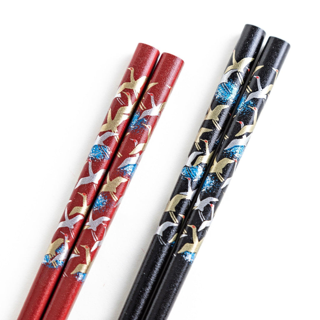 A boxed set of two pairs of chopsticks, one with a black and one with crane patterns on the handles.