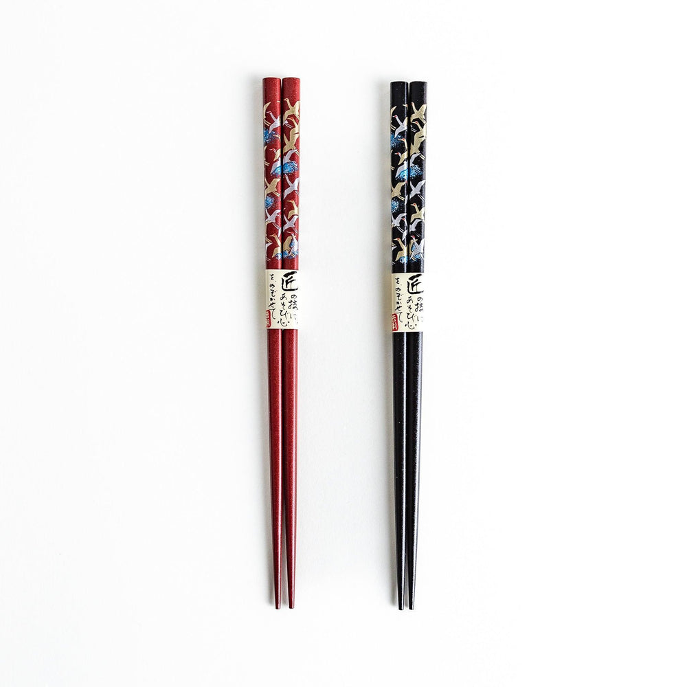 A boxed set of two pairs of chopsticks, one with a black and one with crane patterns on the handles.