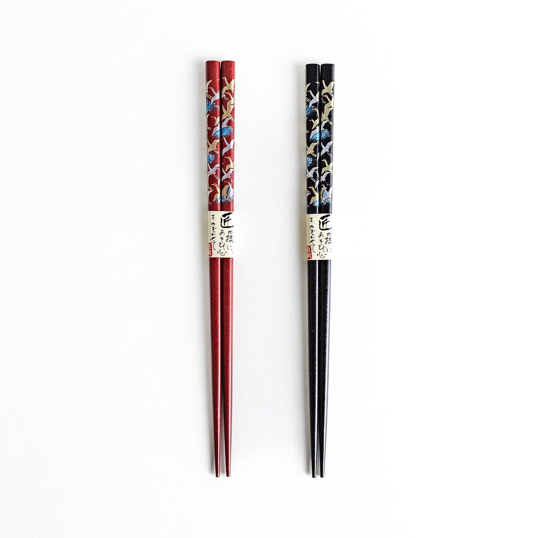 A boxed set of two pairs of chopsticks, one with a black and one with crane patterns on the handles.