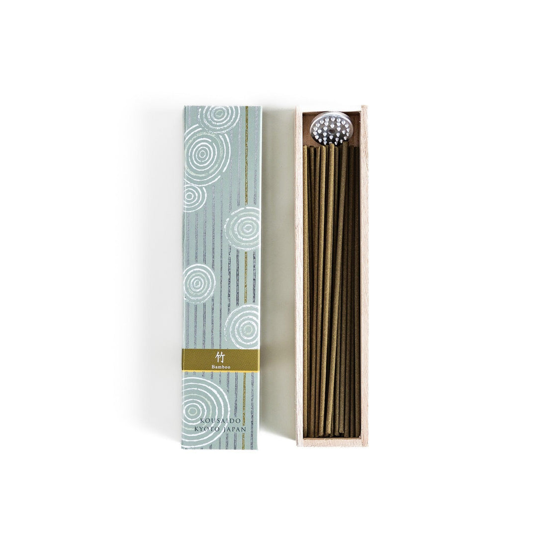 Green incense sticks in a light wooden box with soft green packaging featuring white circular patterns design.