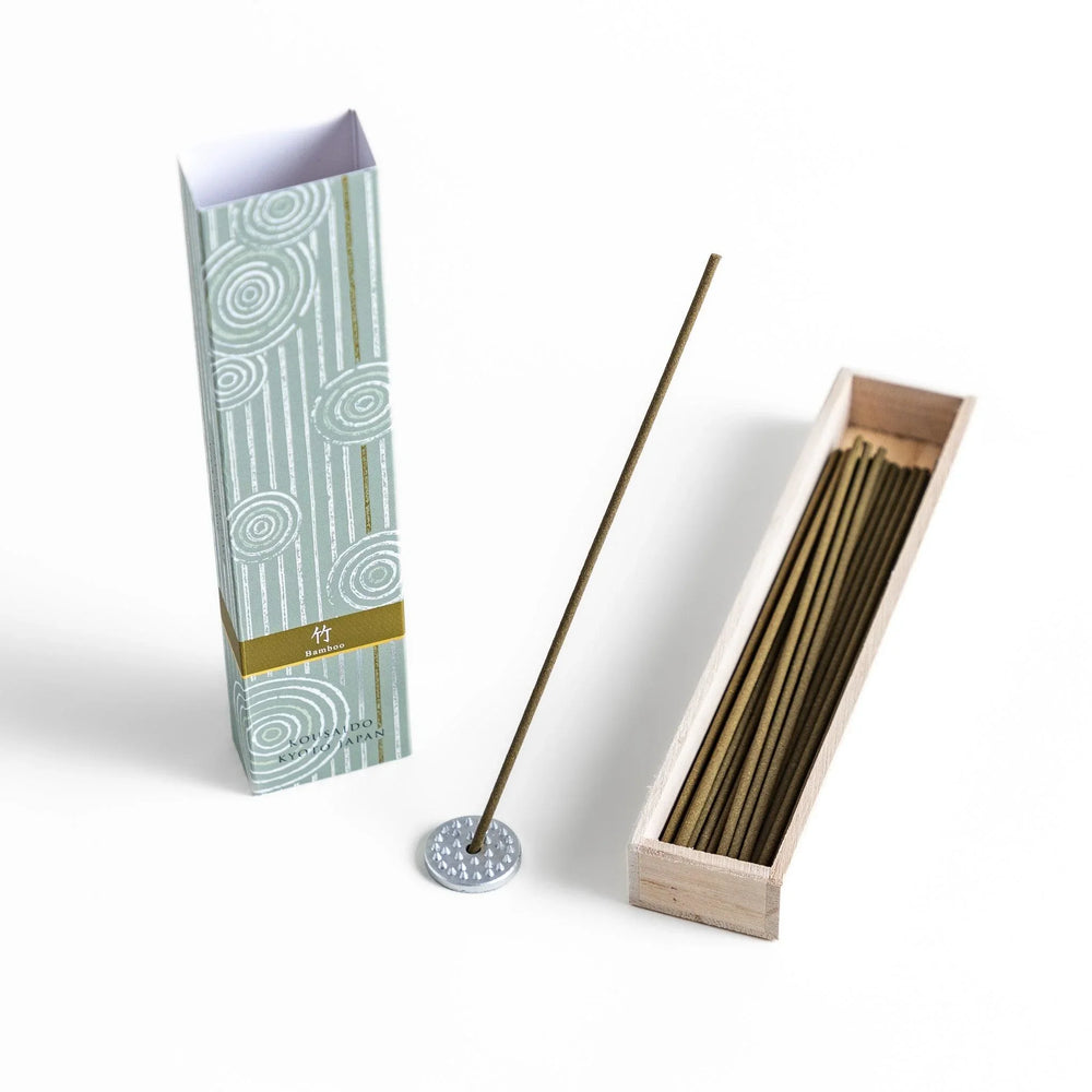 Green incense sticks in a light wooden box with soft green packaging featuring white circular patterns design.