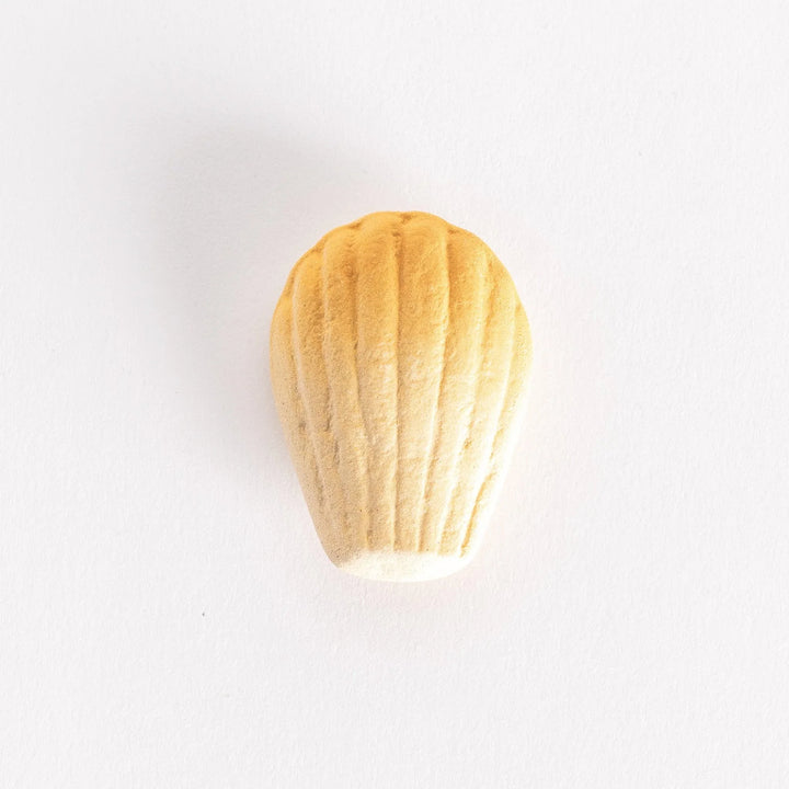 A ceramic chopstick rest shaped like a golden madeleine, showcasing its textured ridges on a white background.