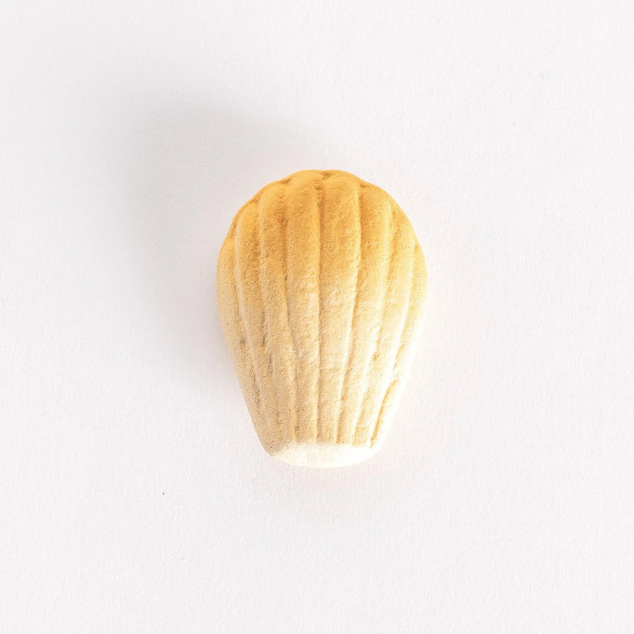 A ceramic chopstick rest shaped like a golden madeleine, showcasing its textured ridges on a white background.