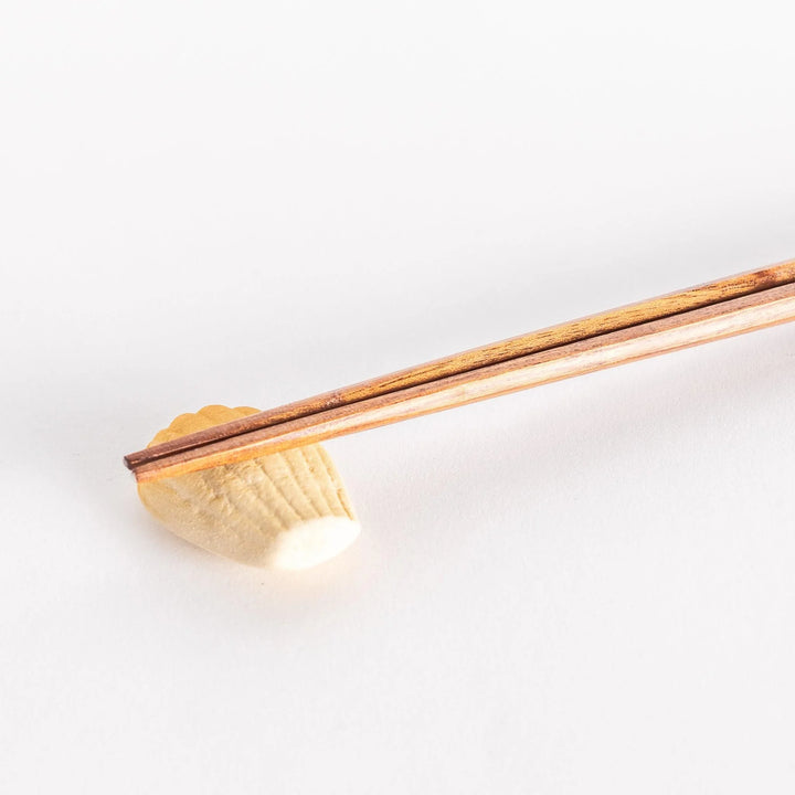 Madeleine shaped ceramic chopstick rest with soft golden tone adding sweet charm to table setting.