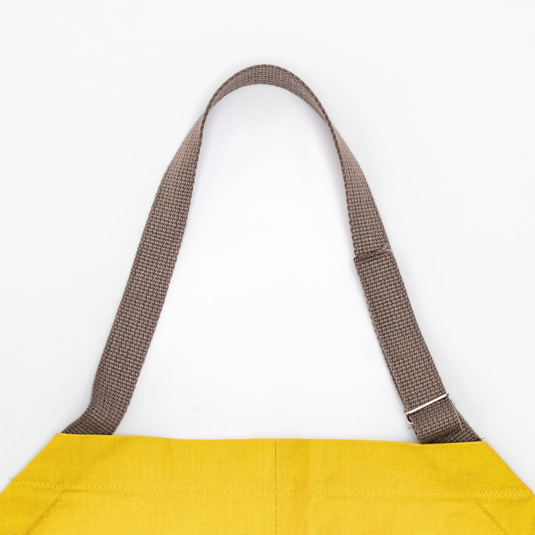 Stylish mustard yellow Japanese apron from our kitchen linens collection, featuring pockets and adjustable straps.