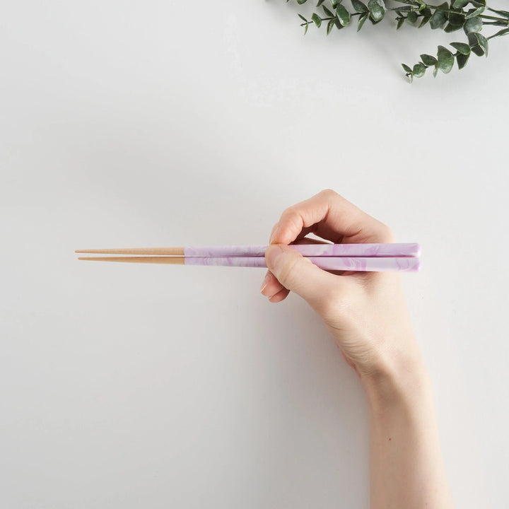 A hand holds the Lavender Breeze Fusion Chopsticks, showcasing the sleek purple design and natural wood.