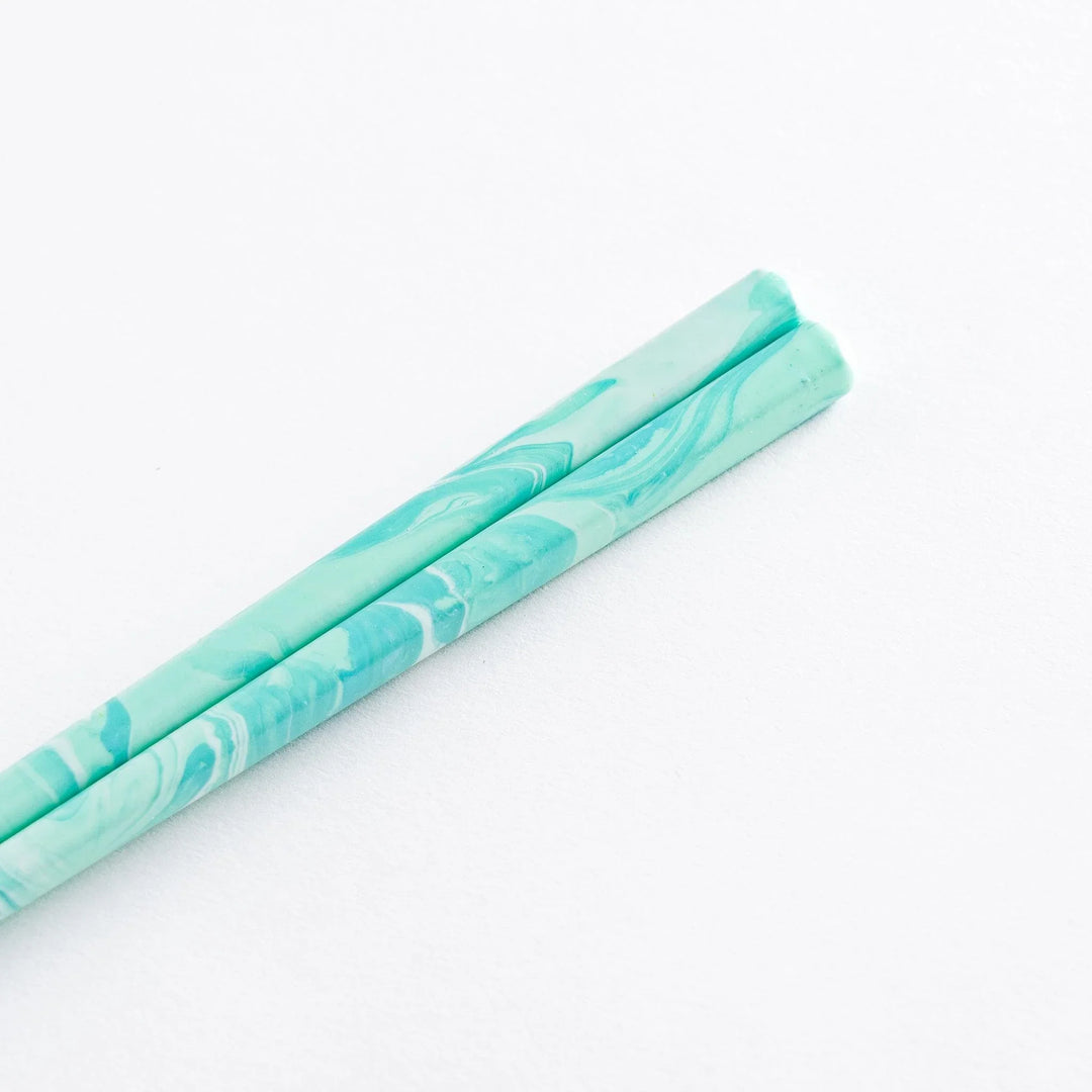Elegant aqua chopsticks positioned against a minimalistic background, showcasing the beautiful marbling and style.