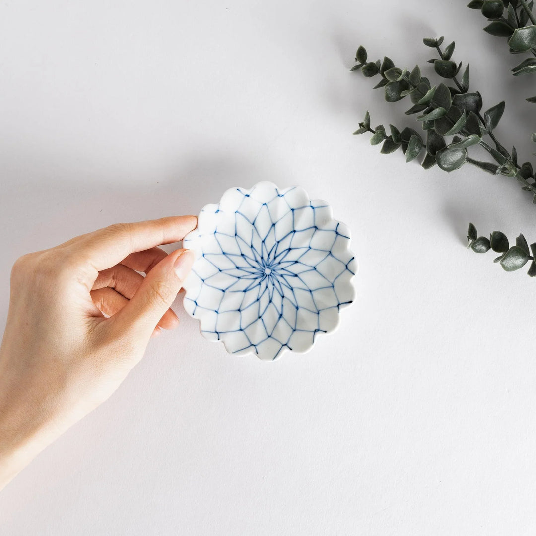 White sauce dish with a blue chrysanthemum mesh pattern and scalloped edges.