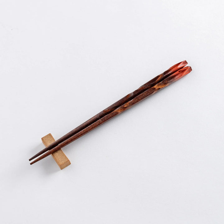Dark brown chopsticks with textured design and matching rests neatly arranged in wooden presentation box.
