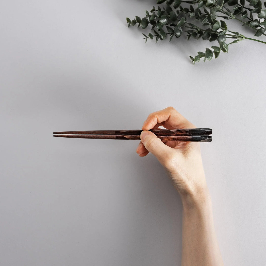 Dark brown chopsticks with textured design and matching rests neatly arranged in wooden presentation box.