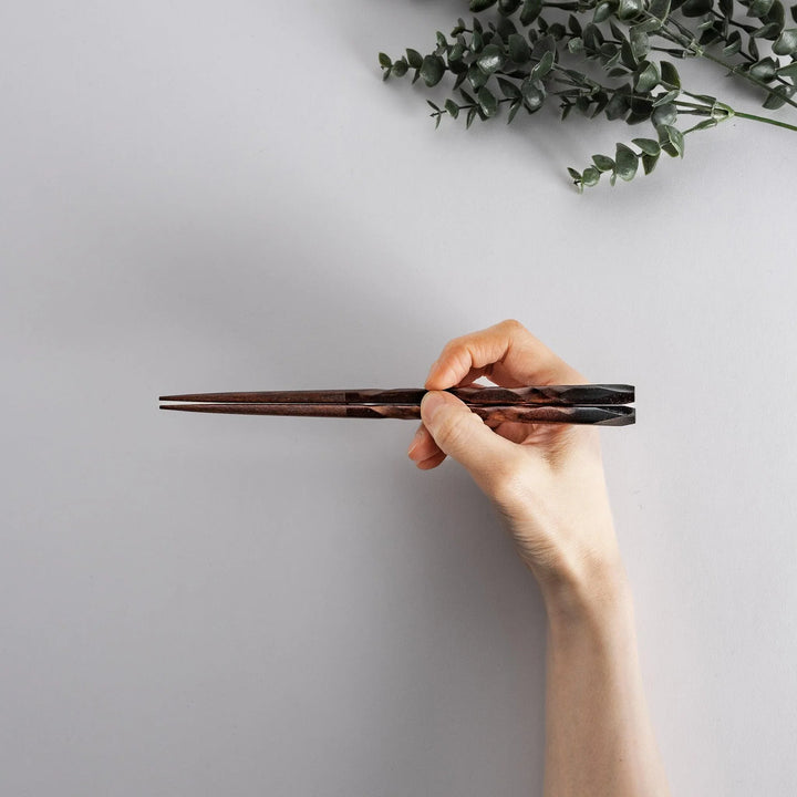 Dark brown chopsticks with textured design and matching rests neatly arranged in wooden presentation box.