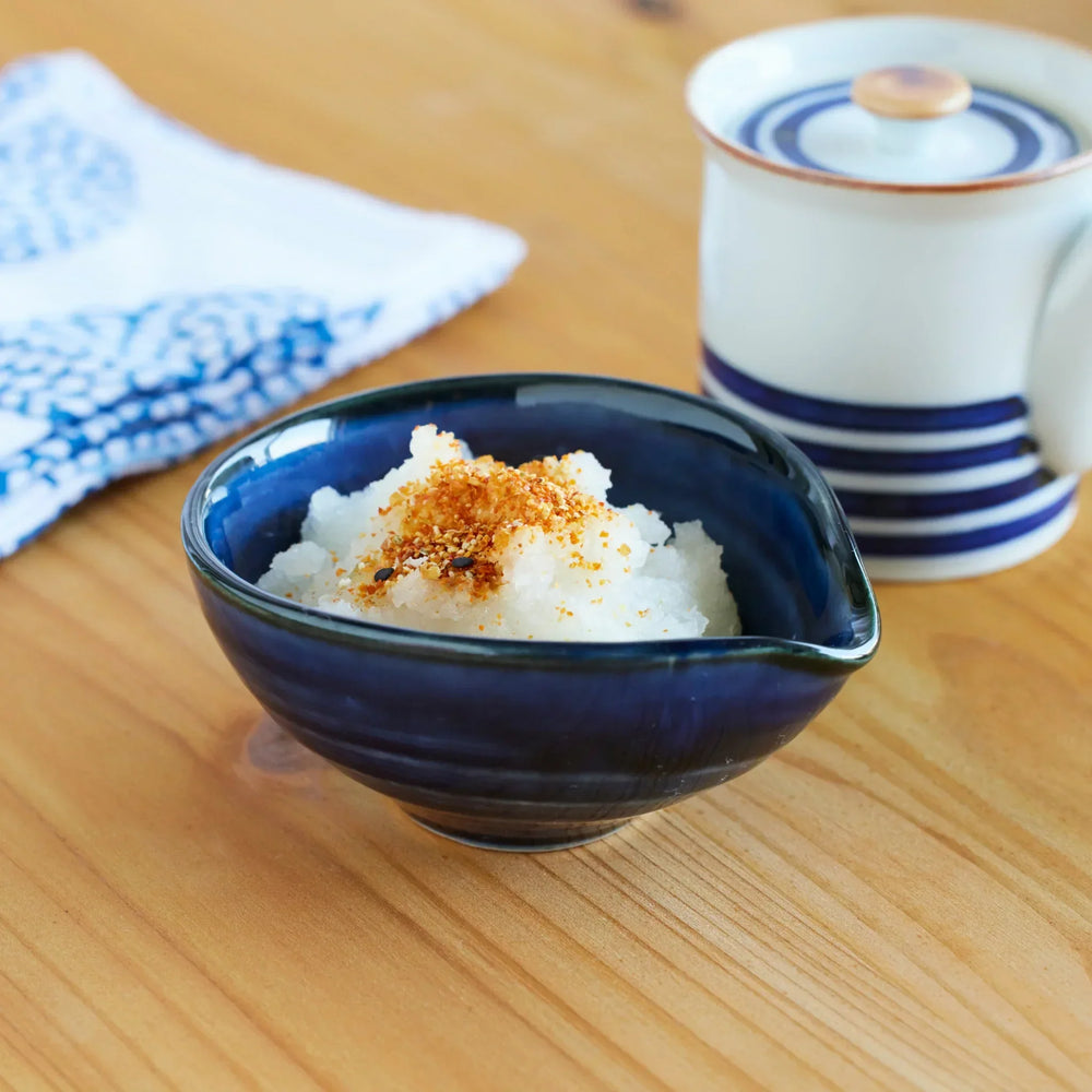 Japanese indigo blue ceramic bowl filled with grated daikon radish topped with seasoning, perfect for traditional tableware.