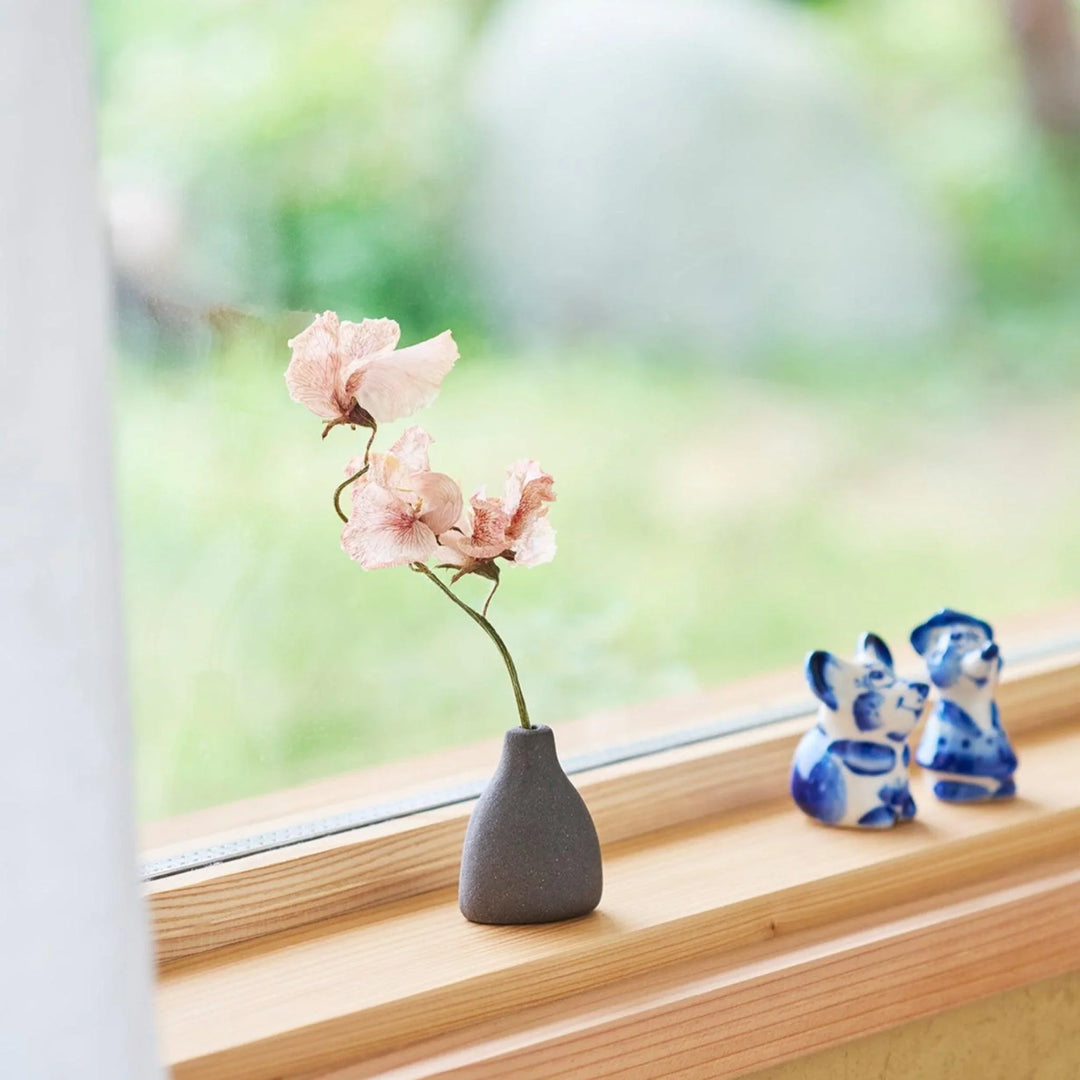 Dark ceramic bud vase with dried flowers, ideal for bringing a modern Japanese touch to any room or table.