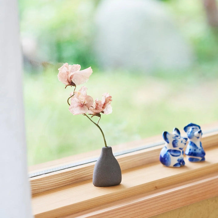 Dark ceramic bud vase with dried flowers, ideal for bringing a modern Japanese touch to any room or table.