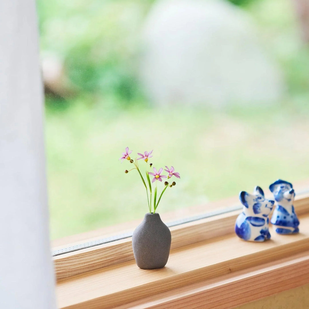 Dark ceramic bud vase with dried flowers, ideal for bringing a modern Japanese touch to any room or table.