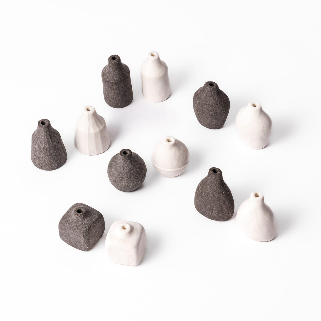 Set of small minimalist ceramic bud vases in black and white tones, each with a unique handcrafted shape on white background