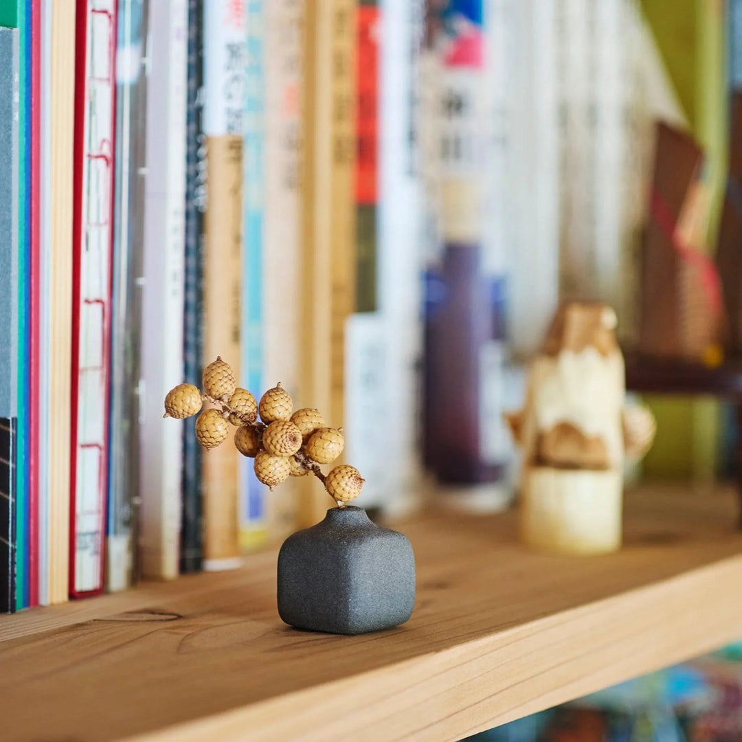 Dark ceramic bud vase with dried flowers, ideal for bringing a modern Japanese touch to any room or table.