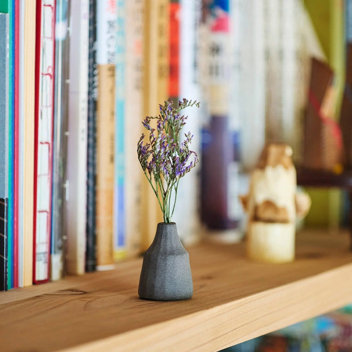 Dark ceramic bud vase with dried flowers, ideal for bringing a modern Japanese touch to any room or table.