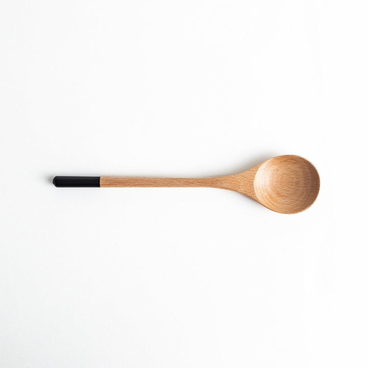 A set of four wooden soup spoons with wide, rounded bowls and colored tips—white, black, blue, and red.