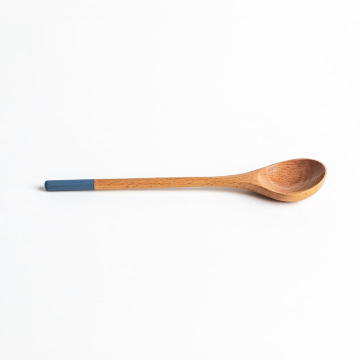 A set of four wooden soup spoons with wide, rounded bowls and colored tips—white, black, blue, and red.