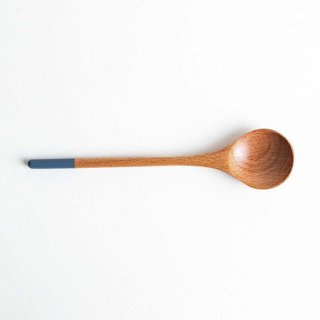 A set of four wooden soup spoons with wide, rounded bowls and colored tips—white, black, blue, and red.