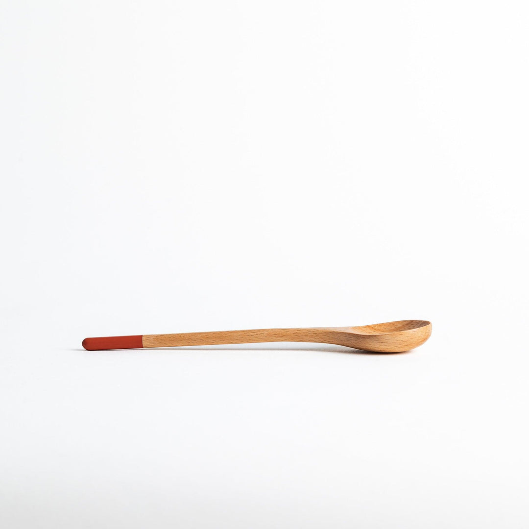 A set of four wooden soup spoons with wide, rounded bowls and colored tips—white, black, blue, and red.