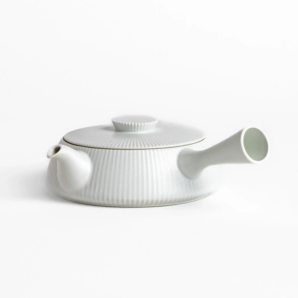 Minimalist ribbed white teapot with sleek spout and round textured lid adding elegance to modern tea sets.