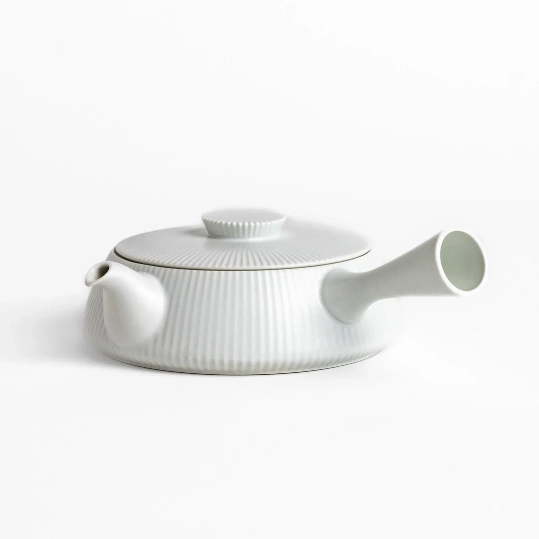 Minimalist ribbed white teapot with sleek spout and round textured lid adding elegance to modern tea sets.