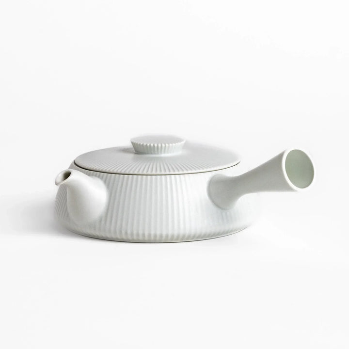 Minimalist ribbed white teapot with sleek spout and round textured lid adding elegance to modern tea sets.