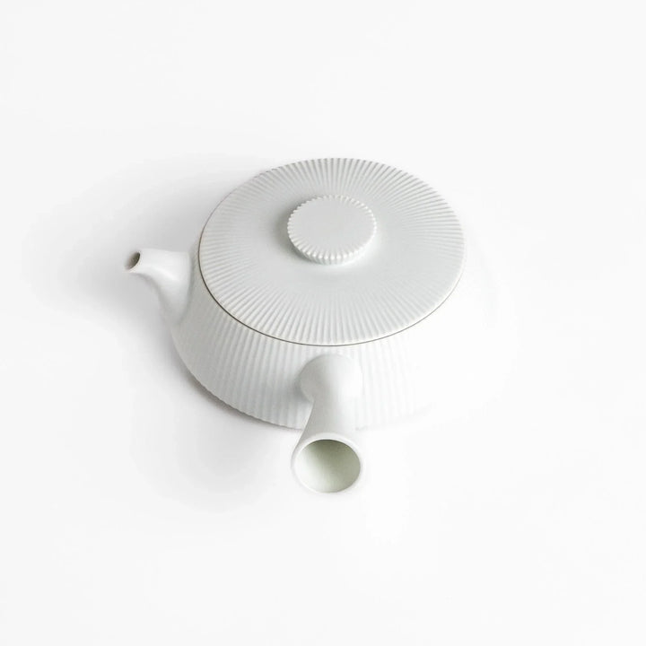 Minimalist ribbed white teapot with sleek spout and round textured lid adding elegance to modern tea sets.