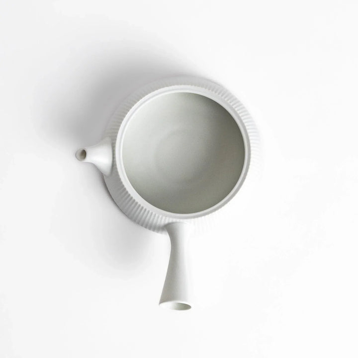 Minimalist ribbed white teapot with sleek spout and round textured lid adding elegance to modern tea sets.