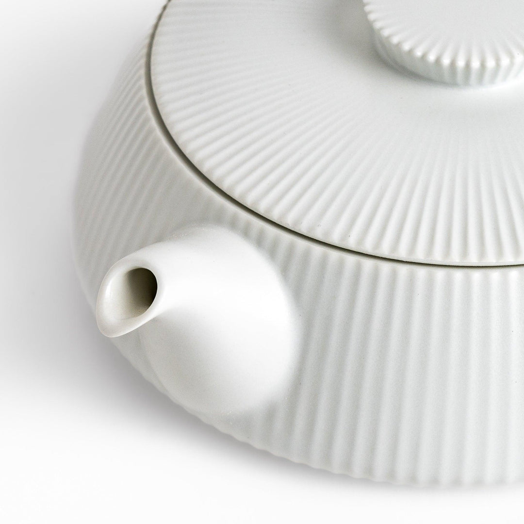 Minimalist ribbed white teapot with sleek spout and round textured lid adding elegance to modern tea sets.