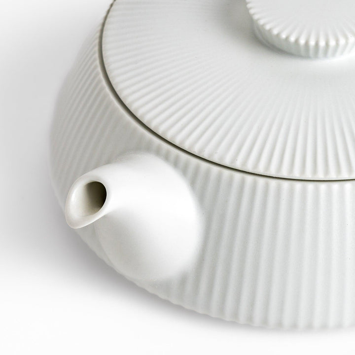 Minimalist ribbed white teapot with sleek spout and round textured lid adding elegance to modern tea sets.