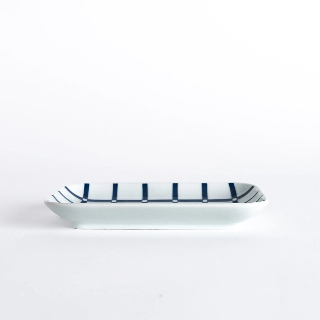 A side view of the rectangular dessert plate, showcasing the indigo lattice design and the plate's slight curvature.