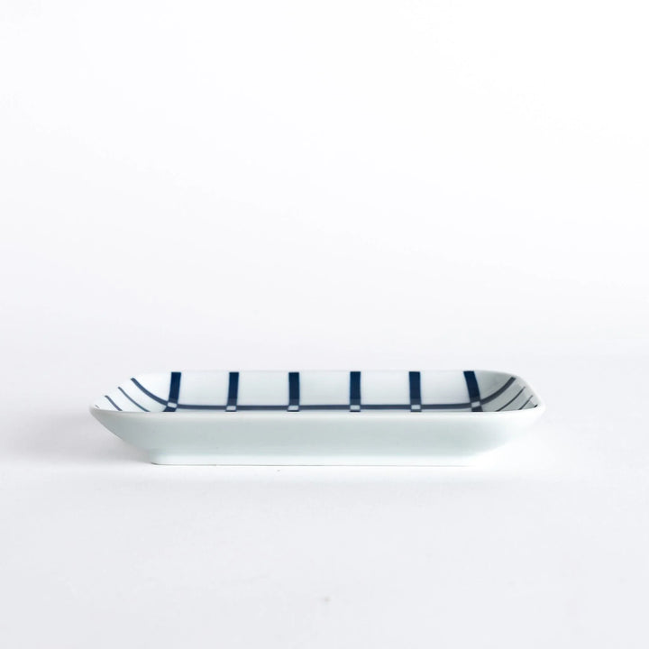 A side view of the rectangular dessert plate, showcasing the indigo lattice design and the plate's slight curvature.
