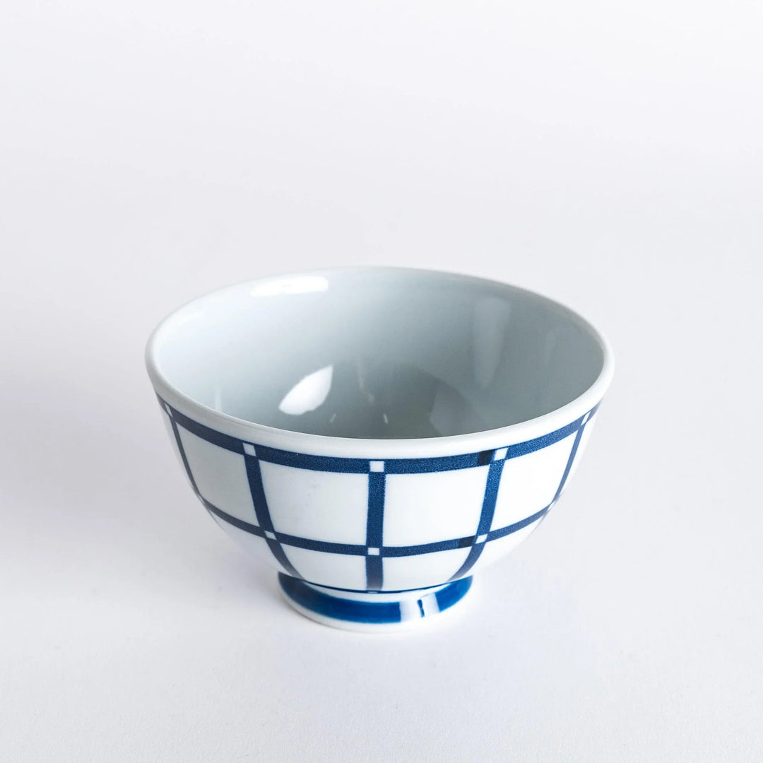 Slightly angled view of the Modern Indigo Lattice Rice Bowl, featuring a crisp navy blue grid pattern with a smooth white finish.