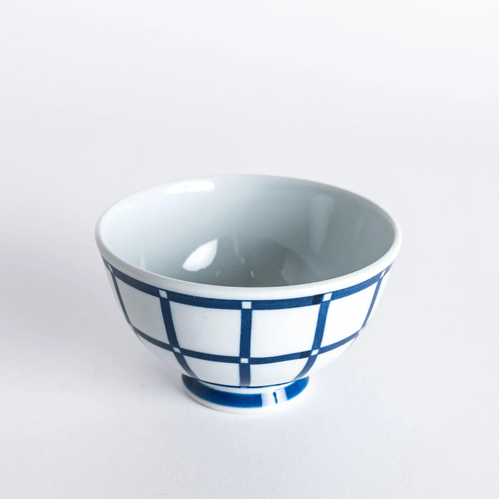 Slightly angled view of the Modern Indigo Lattice Rice Bowl, featuring a crisp navy blue grid pattern with a smooth white finish.