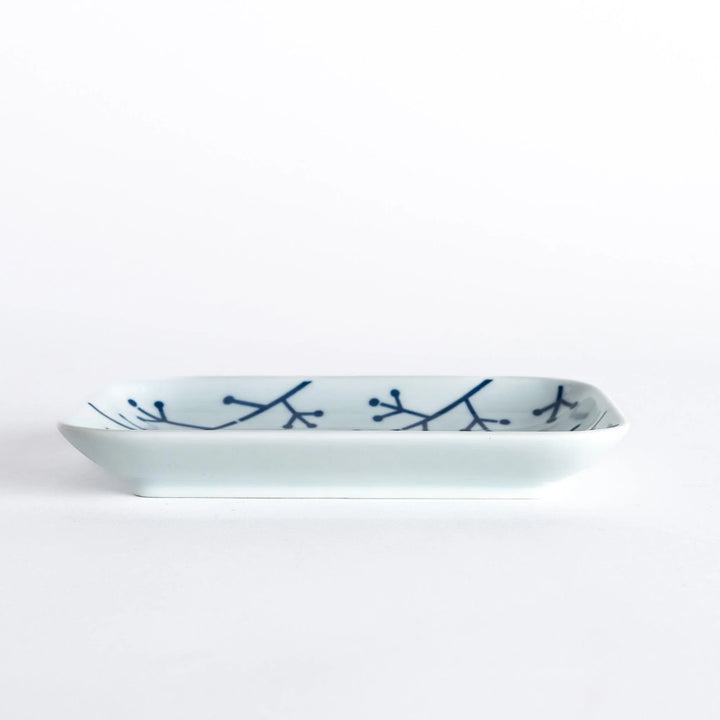 Side view of the dessert plate, emphasizing its elegant profile and the indigo pine branch design.
