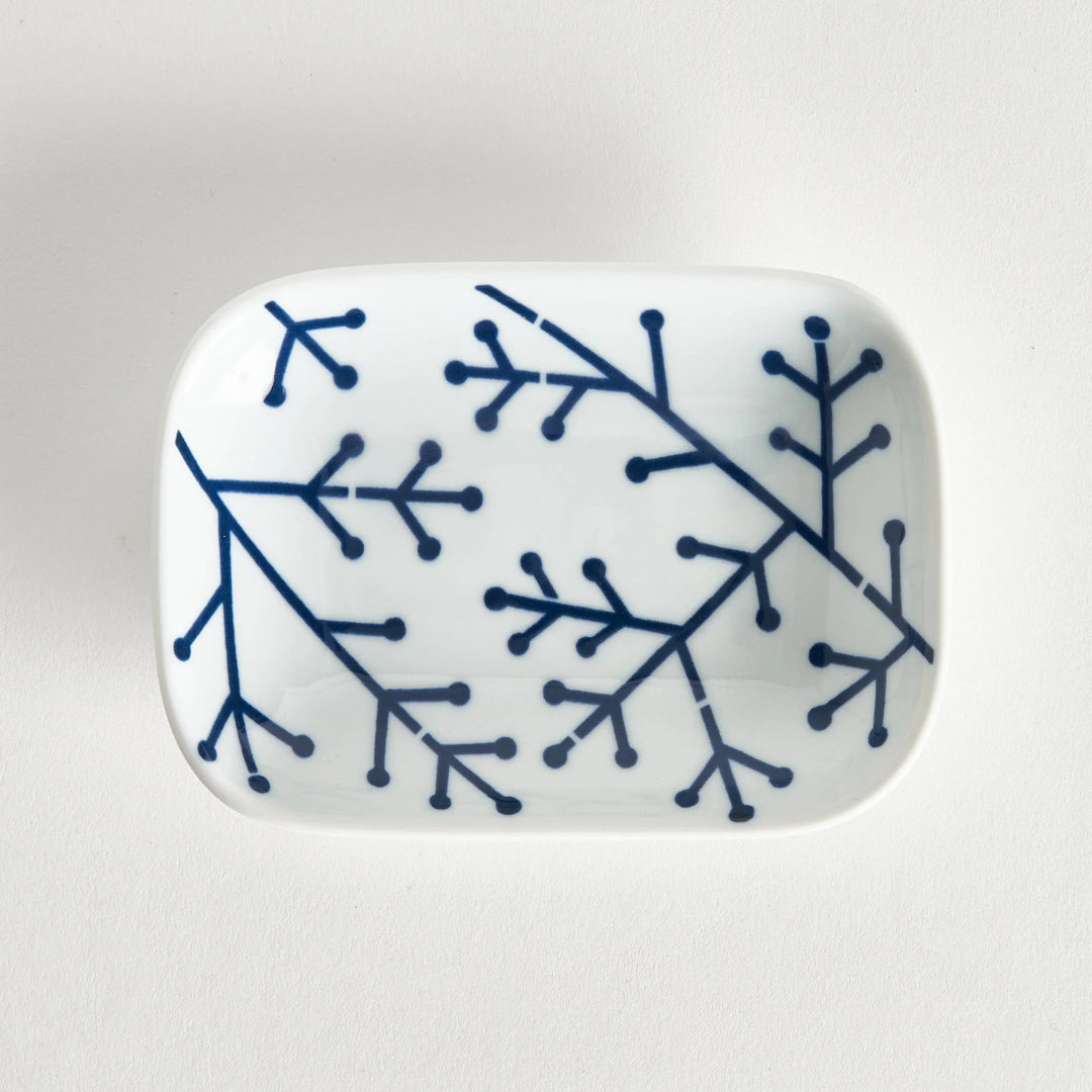 Rectangular white porcelain sauce dish with indigo pine branch motif highlighting modern Japanese style.