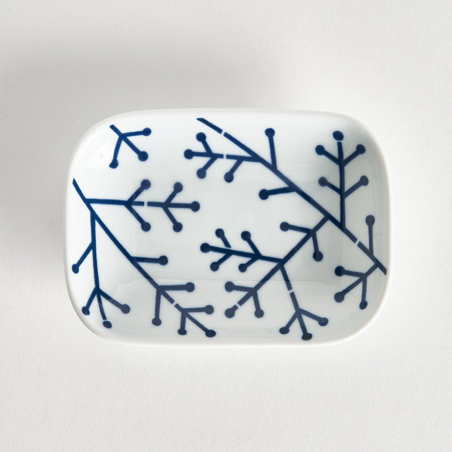 Rectangular white porcelain sauce dish with indigo pine branch motif highlighting modern Japanese style.