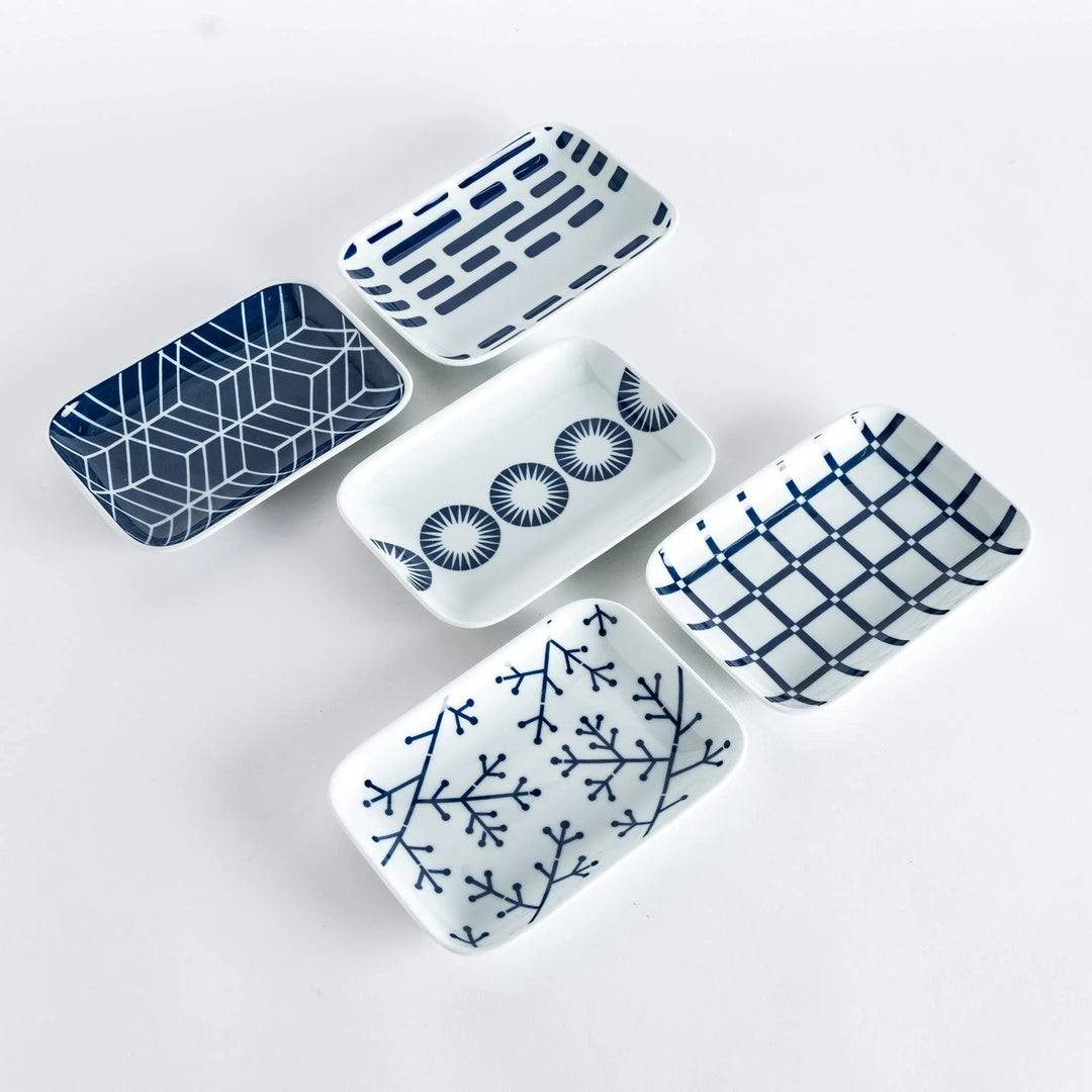 Set of five Japanese dessert plates with indigo geometric line and circle patterns on white porcelain.