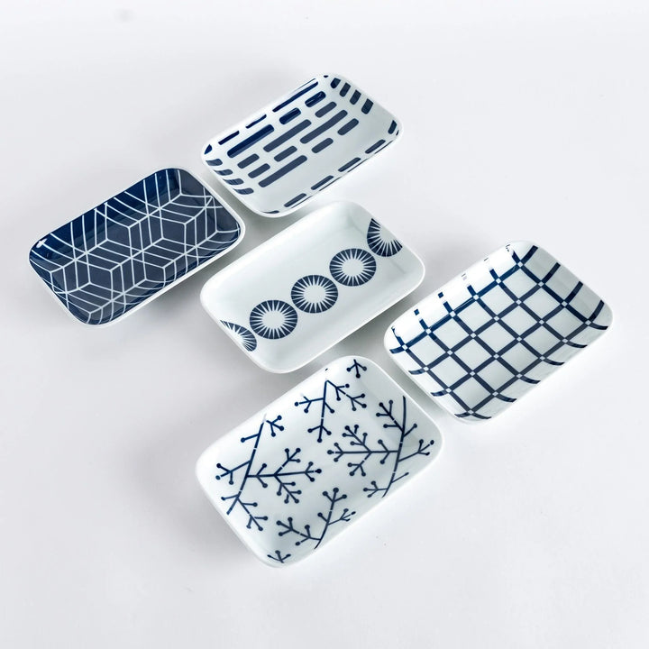 Set of five Japanese dessert plates with indigo geometric line and circle patterns on white porcelain.