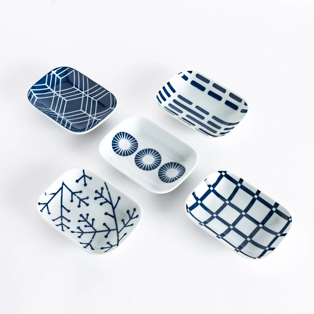 Set of five indigo patterned Japanese sauce dishes featuring geometric shapes lines and circles on white base.