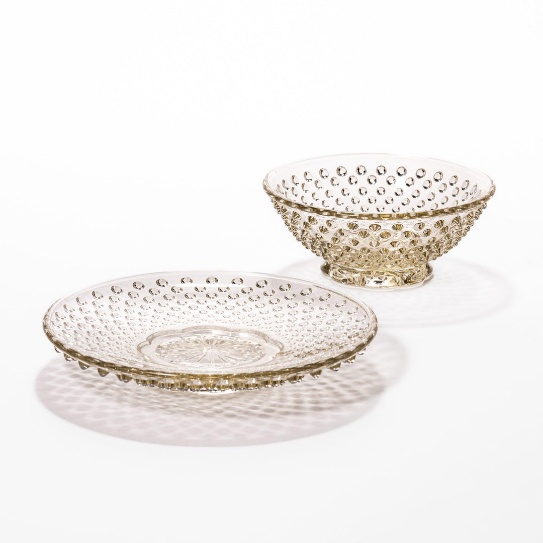 Amber glass dessert bowl and saucer with raised dots and starburst base, perfect for serving refined sweets.