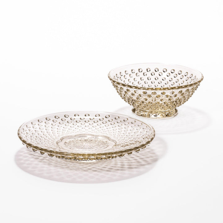 Amber glass dessert bowl and saucer with raised dots and starburst base, perfect for serving refined sweets.