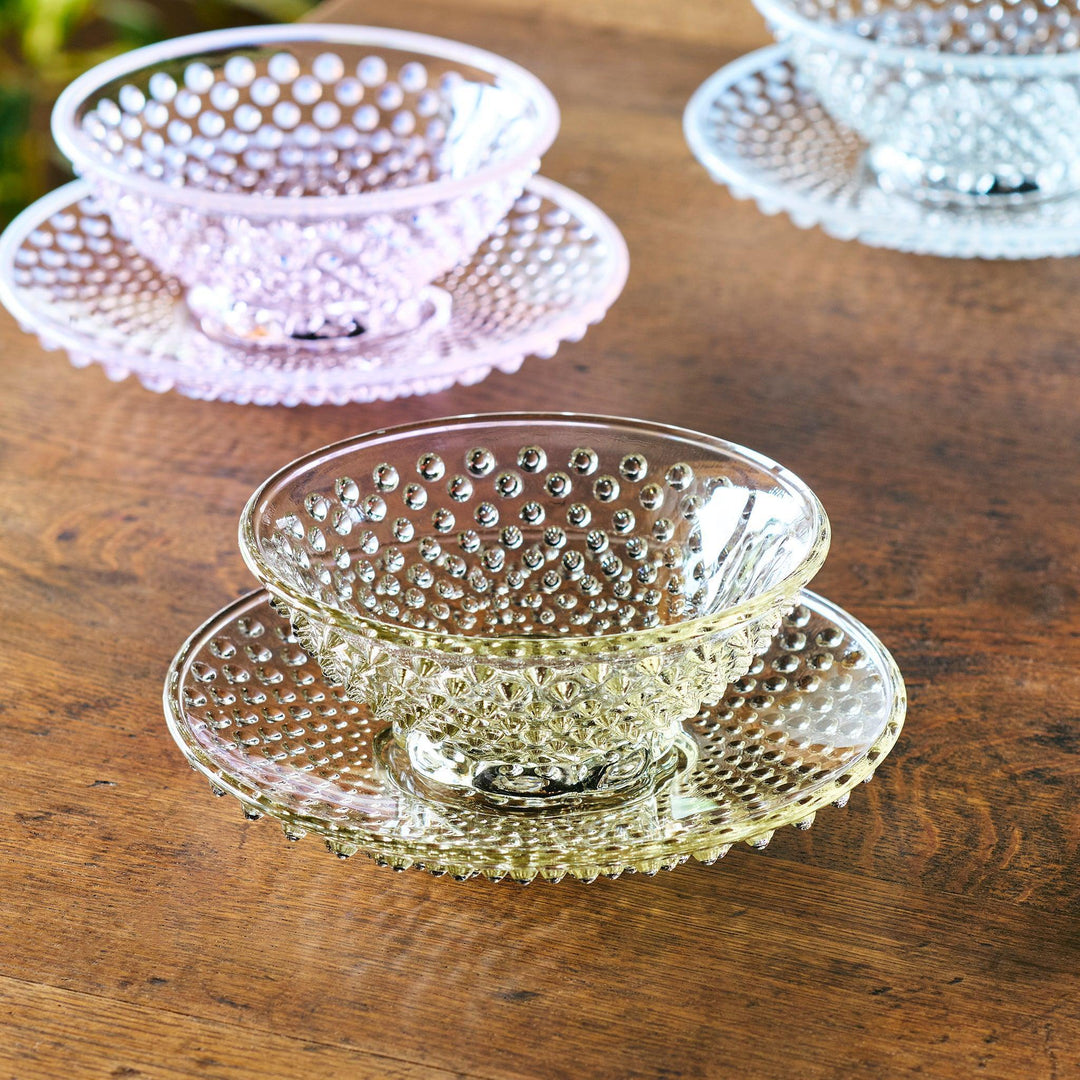 Glass dessert bowl and saucer available in pink, amber, and clear, each with raised dots and radiant base design.
